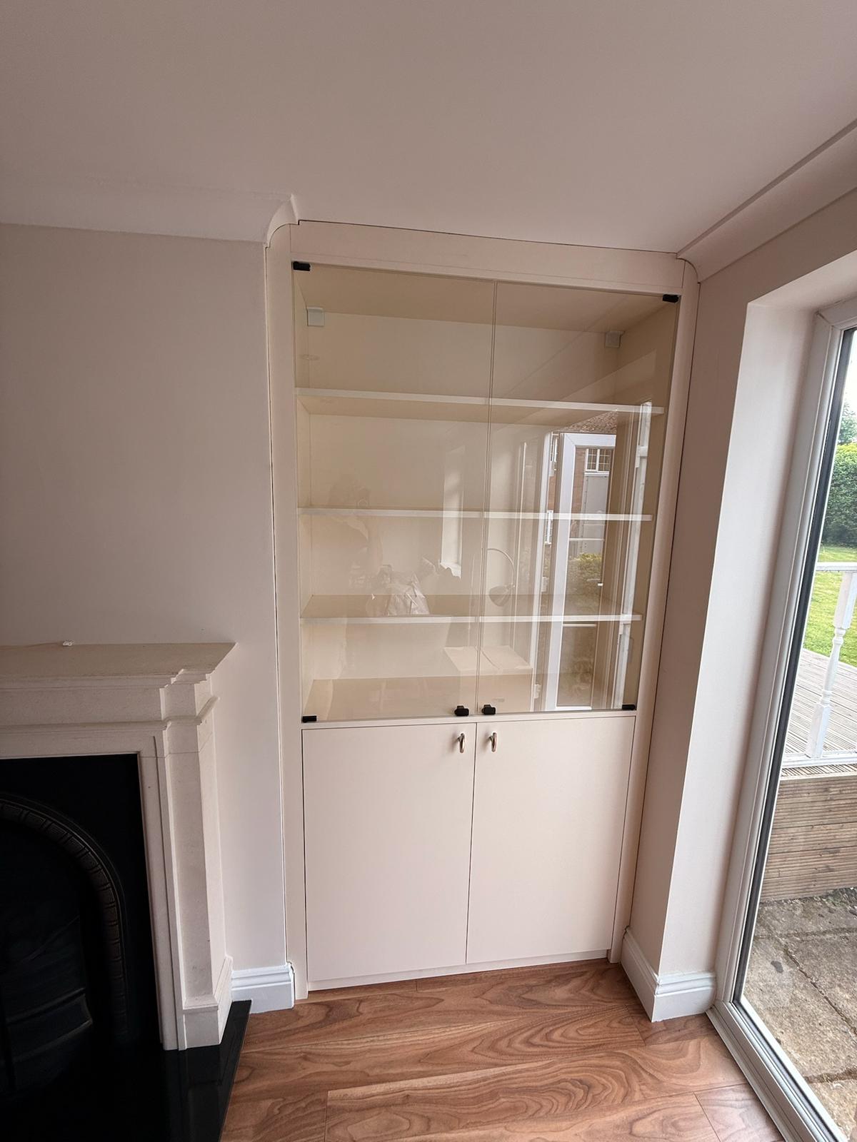 Alcove display cabinet with glass doors and lower cupboards beside a fireplace