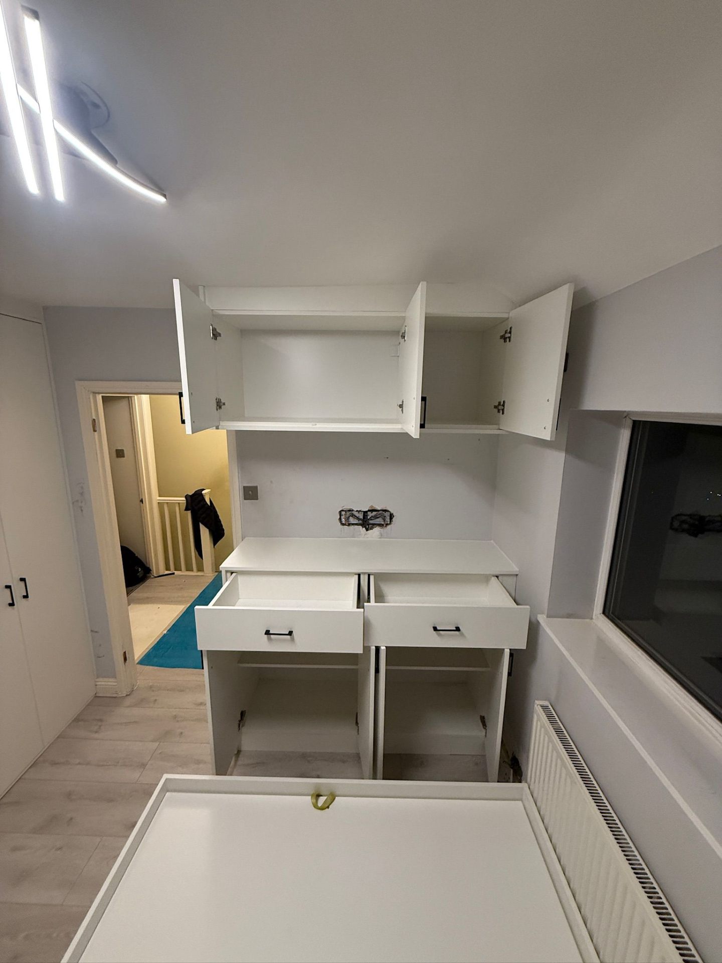 White bedroom cabinets with drawers and wall units during installation