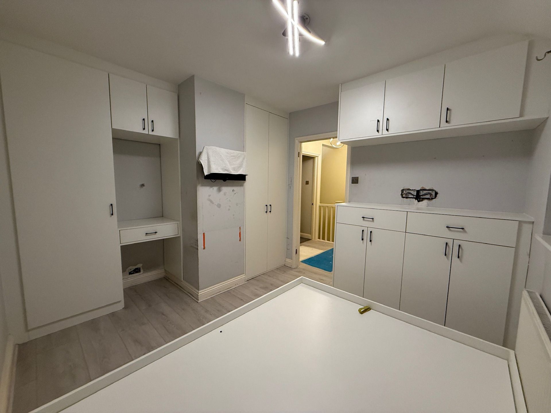 Wide-angle view of a fully fitted white bedroom with floor-to-ceiling storage