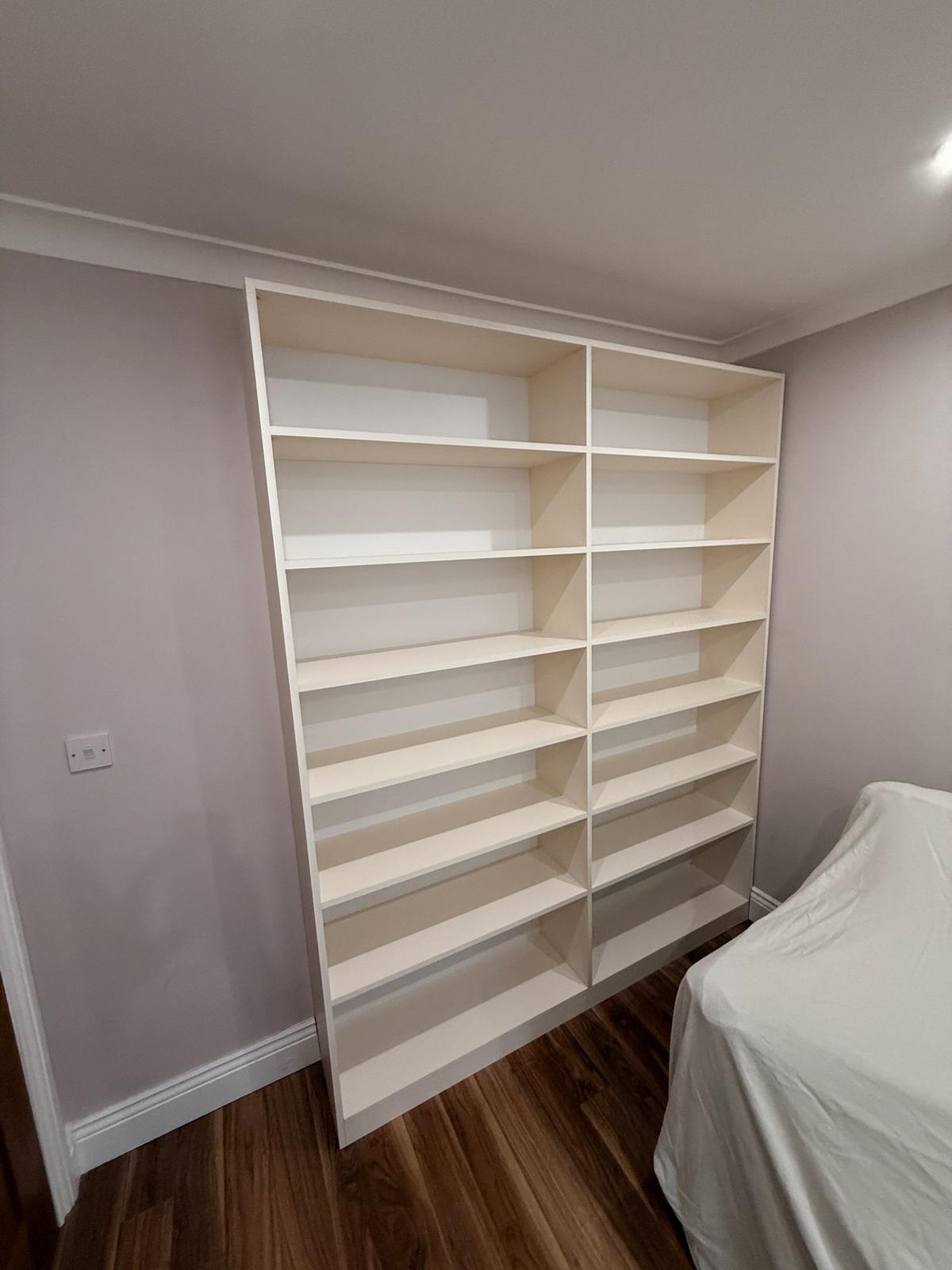 White freestanding bookcase with adjustable shelves in a bedroom