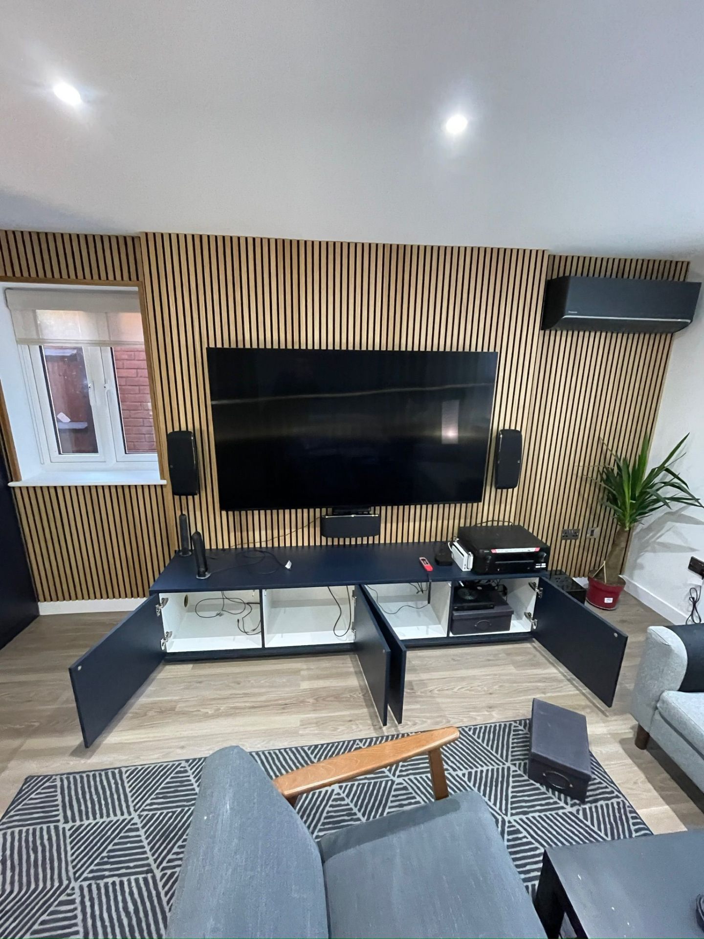 Media wall with slatted panels — cabinets open showing AV equipment storage