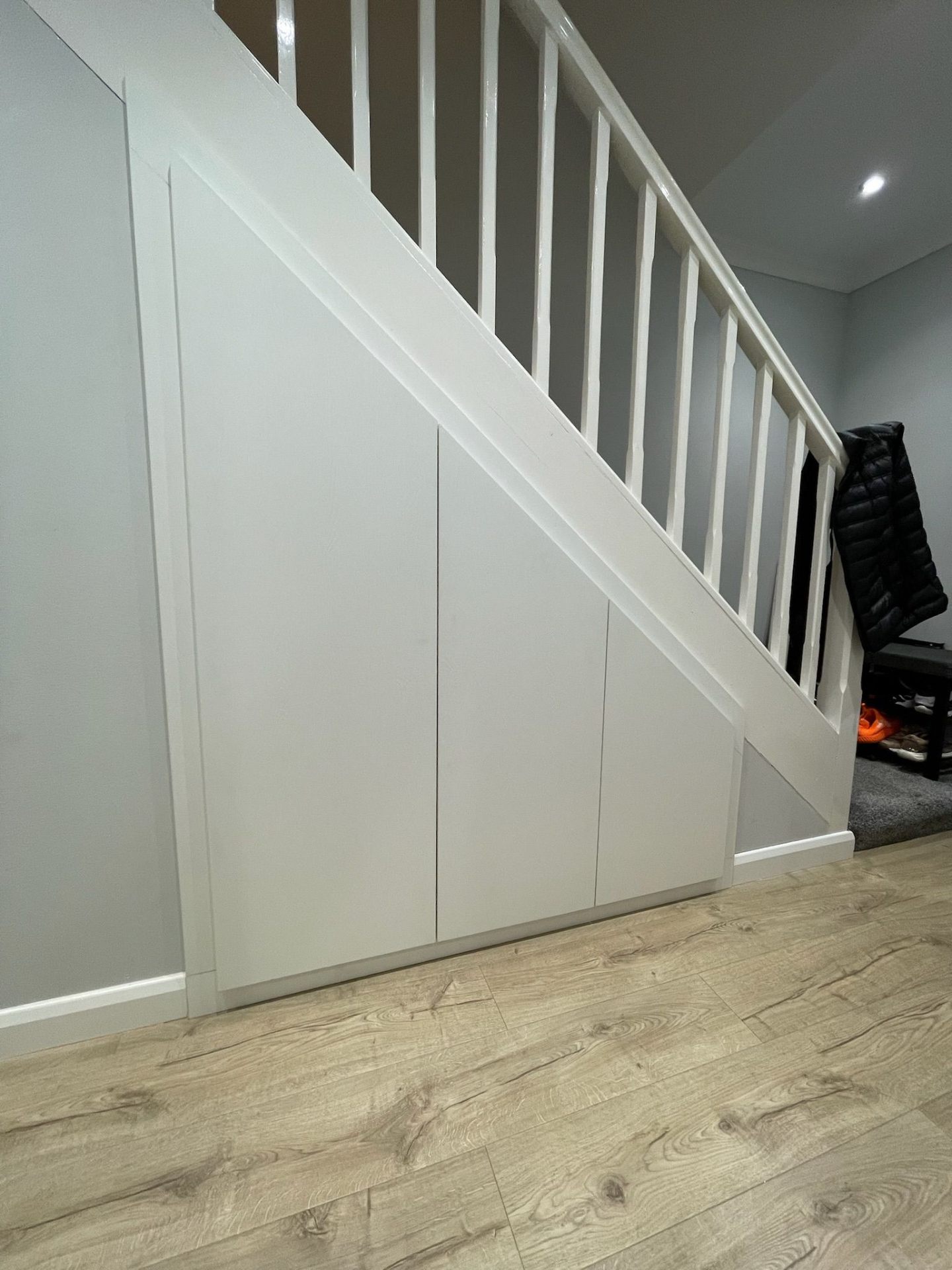 White under-stairs cupboard with panelled doors maximising hallway space