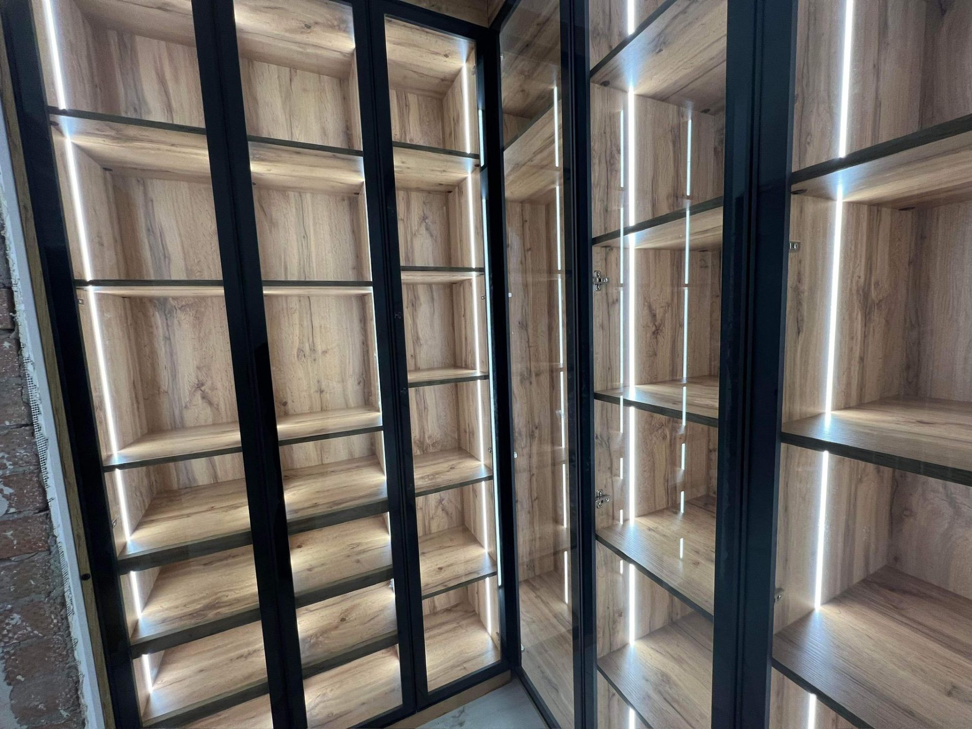 Walk-in wardrobe with oak shelving, glass doors and LED backlighting