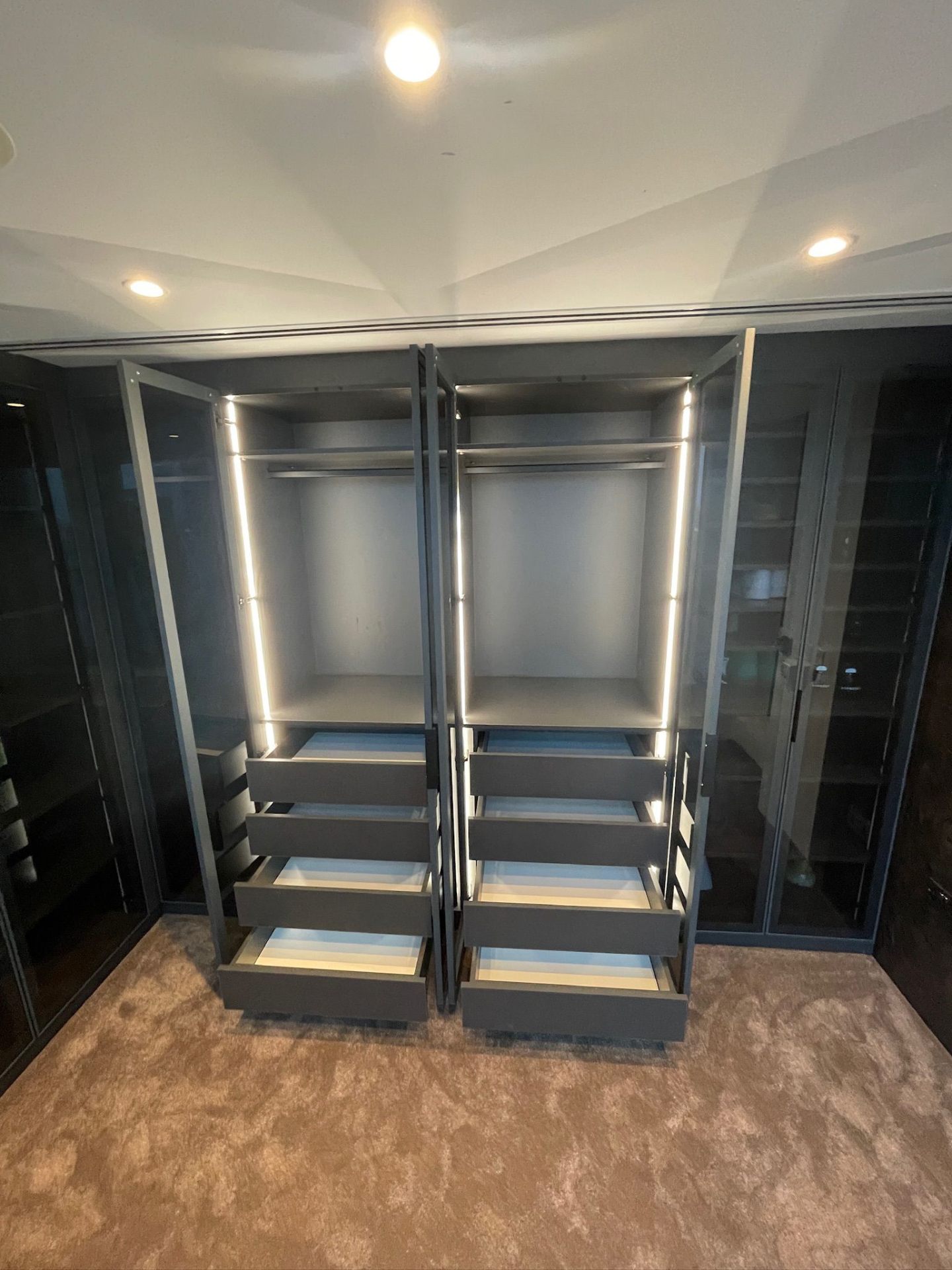 Walk-in wardrobe glass doors open showing shoe shelving and hanging space