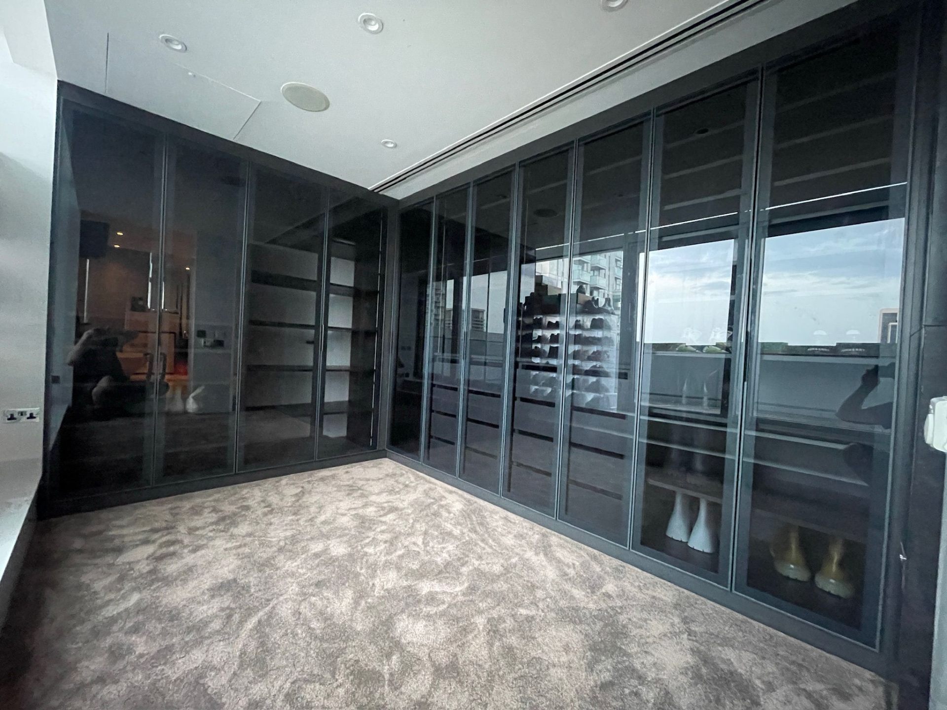 Wide-angle view of a bespoke walk-in wardrobe with glass-fronted cabinets