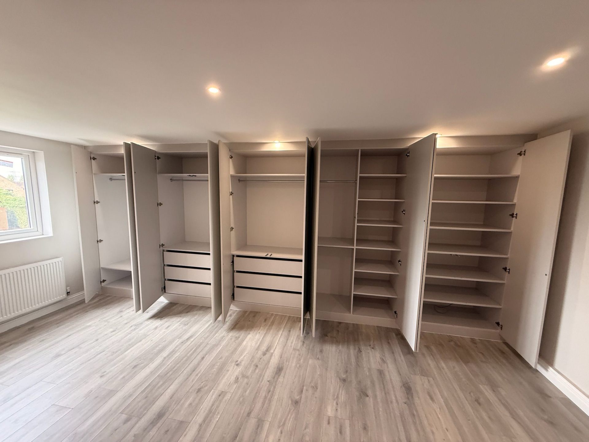 All doors open on a fitted wardrobe revealing customised storage sections