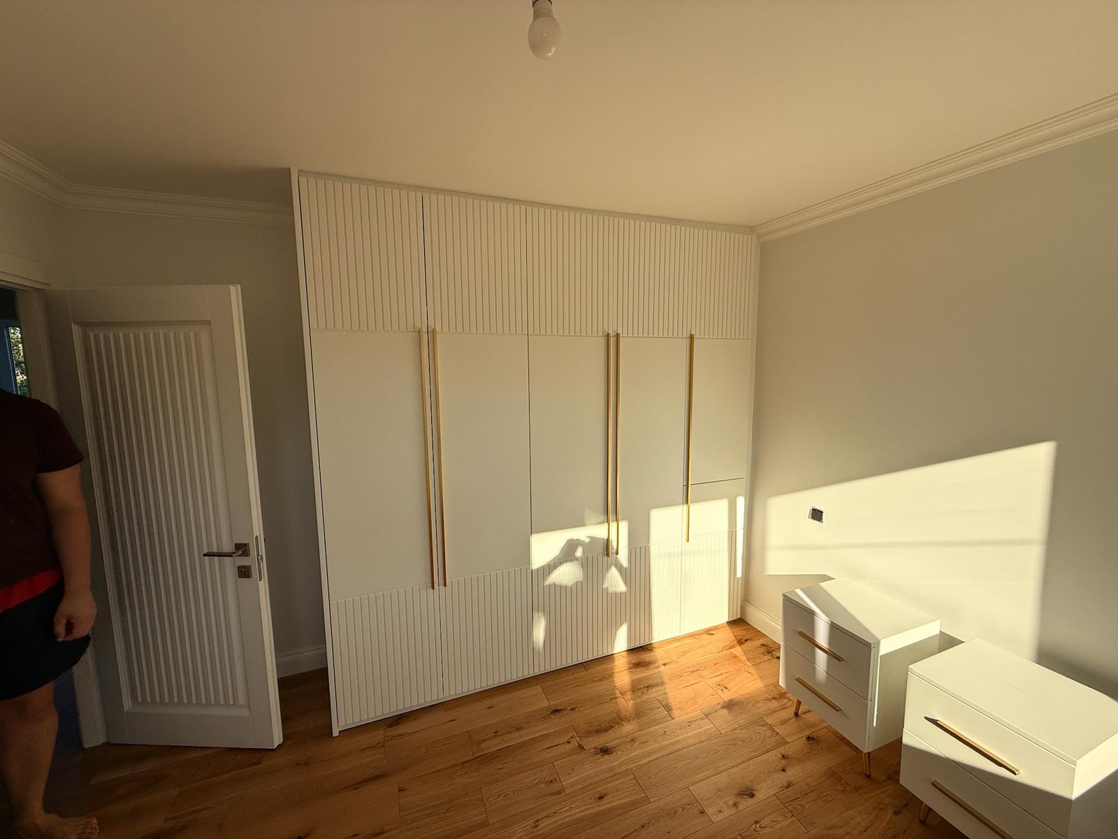 Fitted wardrobe with fluted panel detailing and brass handles in a master bedroom