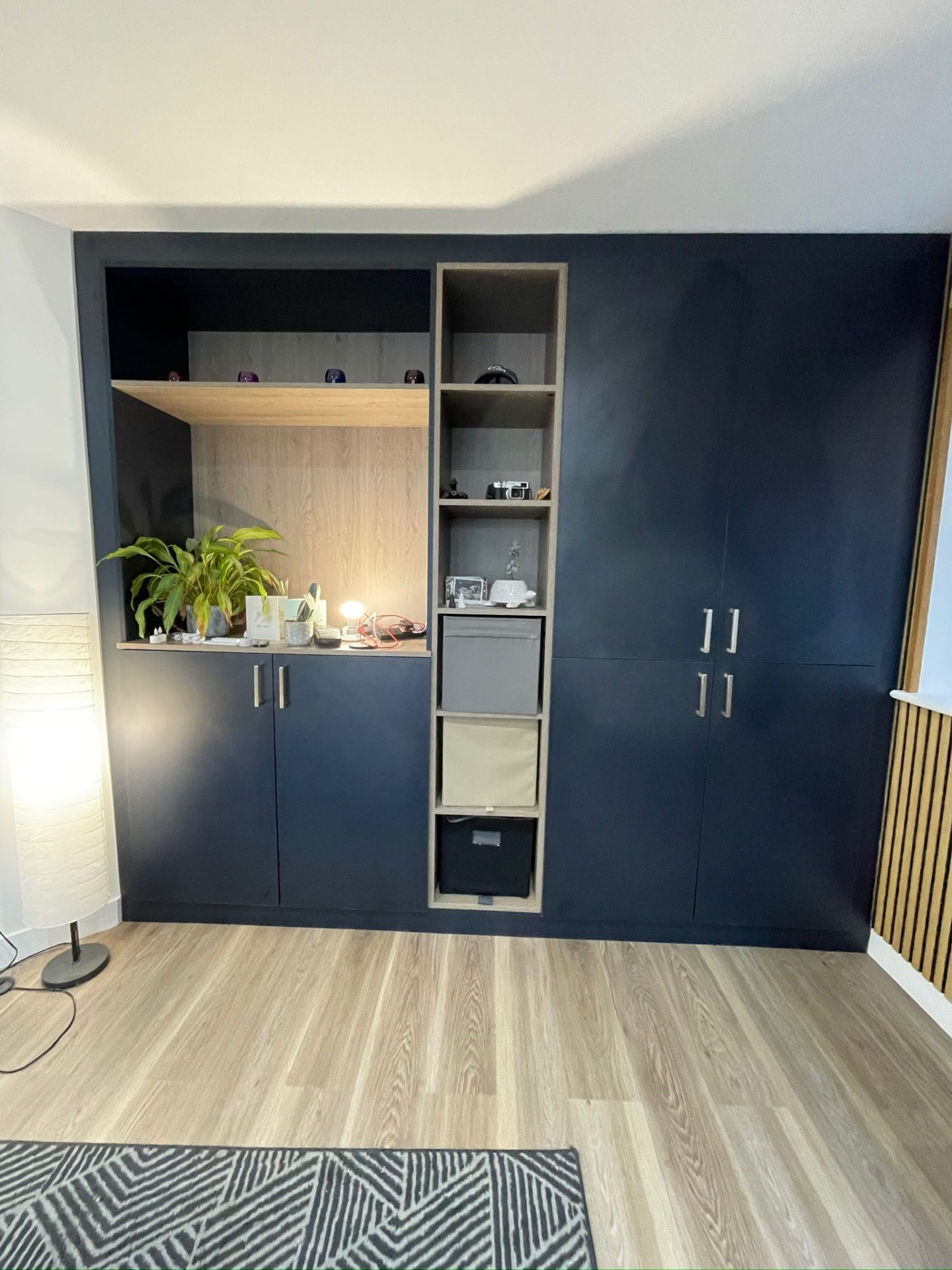 Navy blue bedroom storage wall with oak shelving and display niche