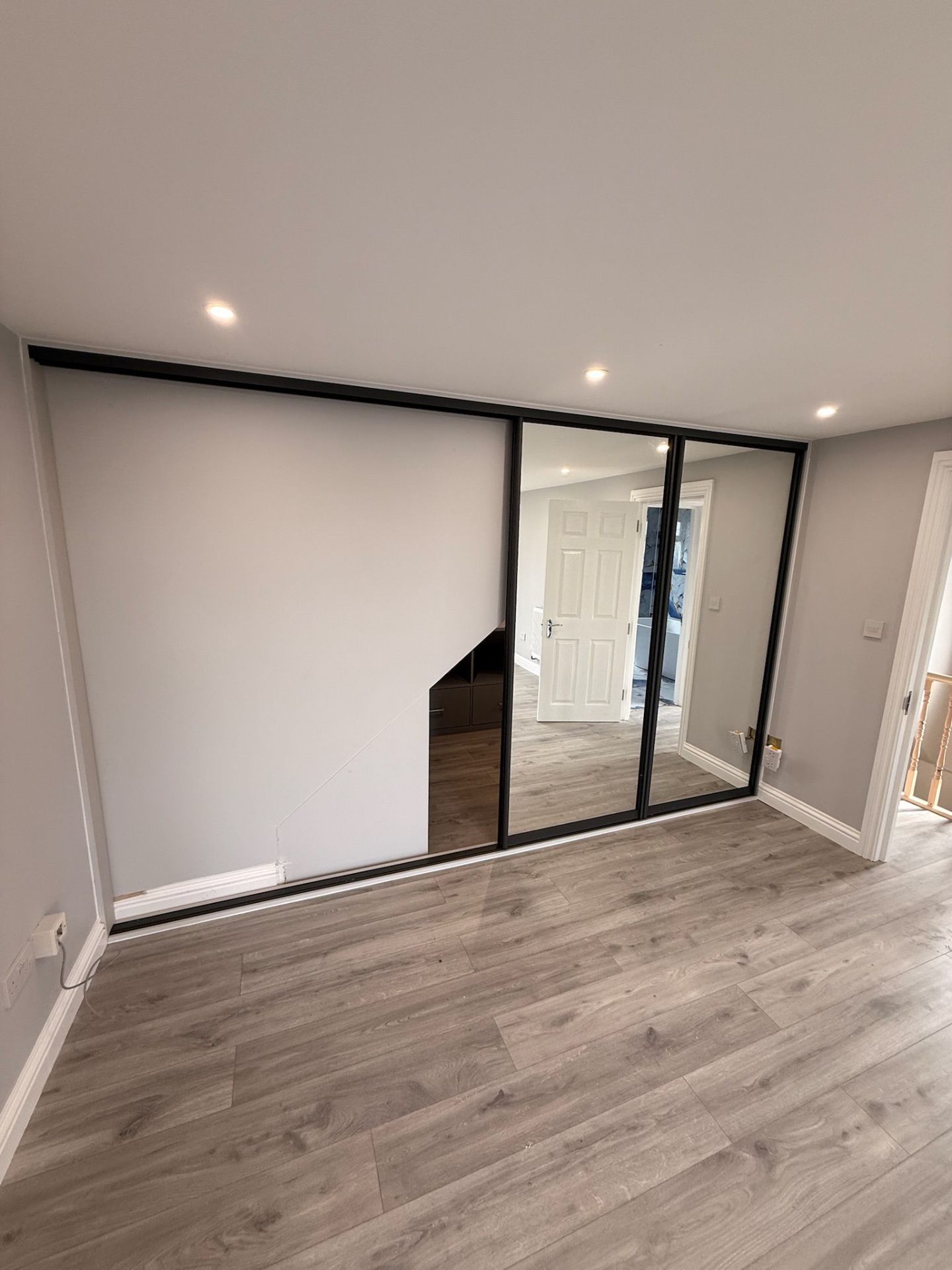 Sliding wardrobe doors with black frame and mirror panel in a loft conversion