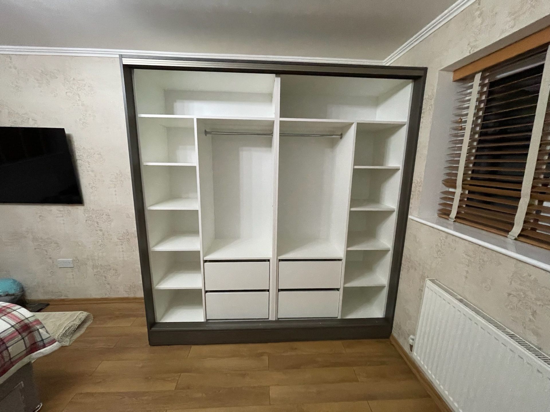 Interior of a fitted wardrobe showing hanging rails, drawers and shelving
