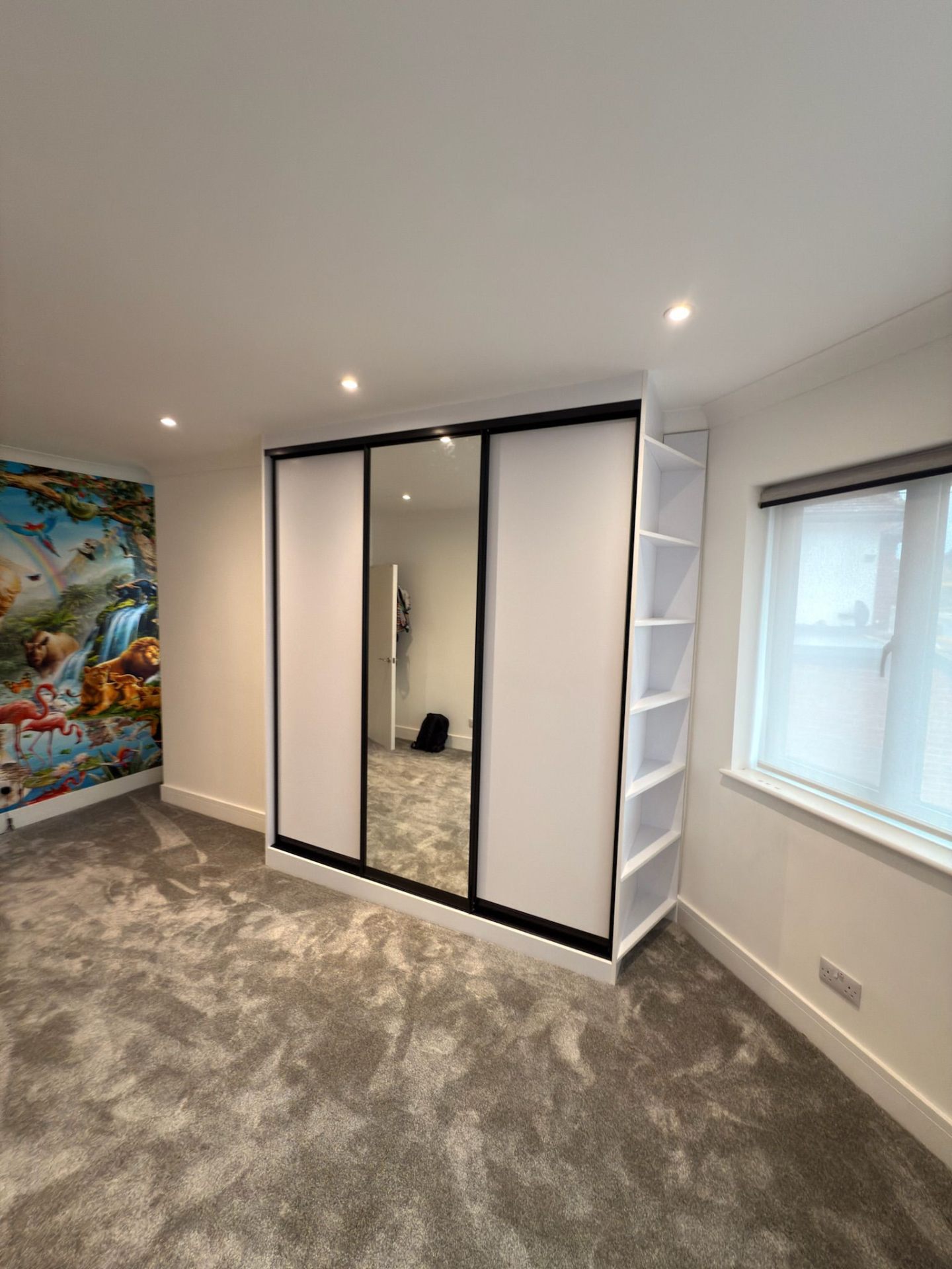 Sliding mirror wardrobe doors with grey frame in a fitted bedroom