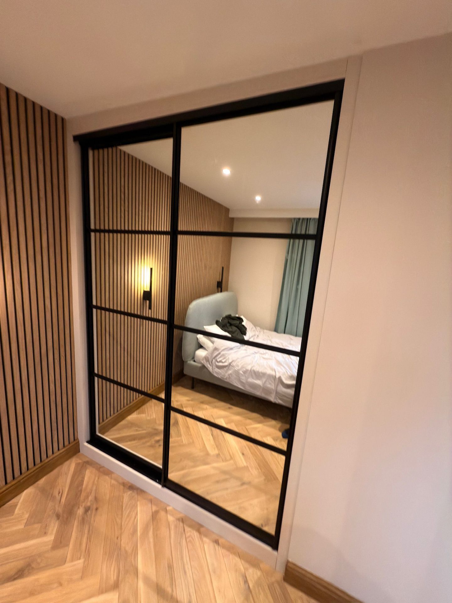 Sliding mirror wardrobe with slatted wood feature wall