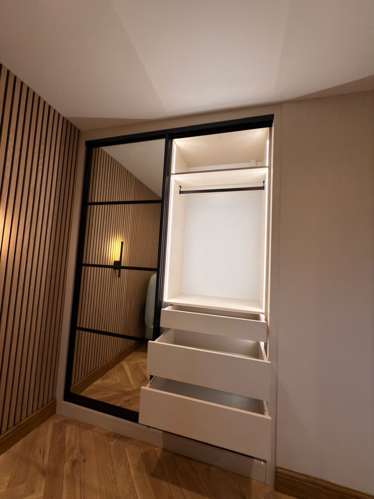 Sliding wardrobe with integrated LED drawers and slatted wall panel