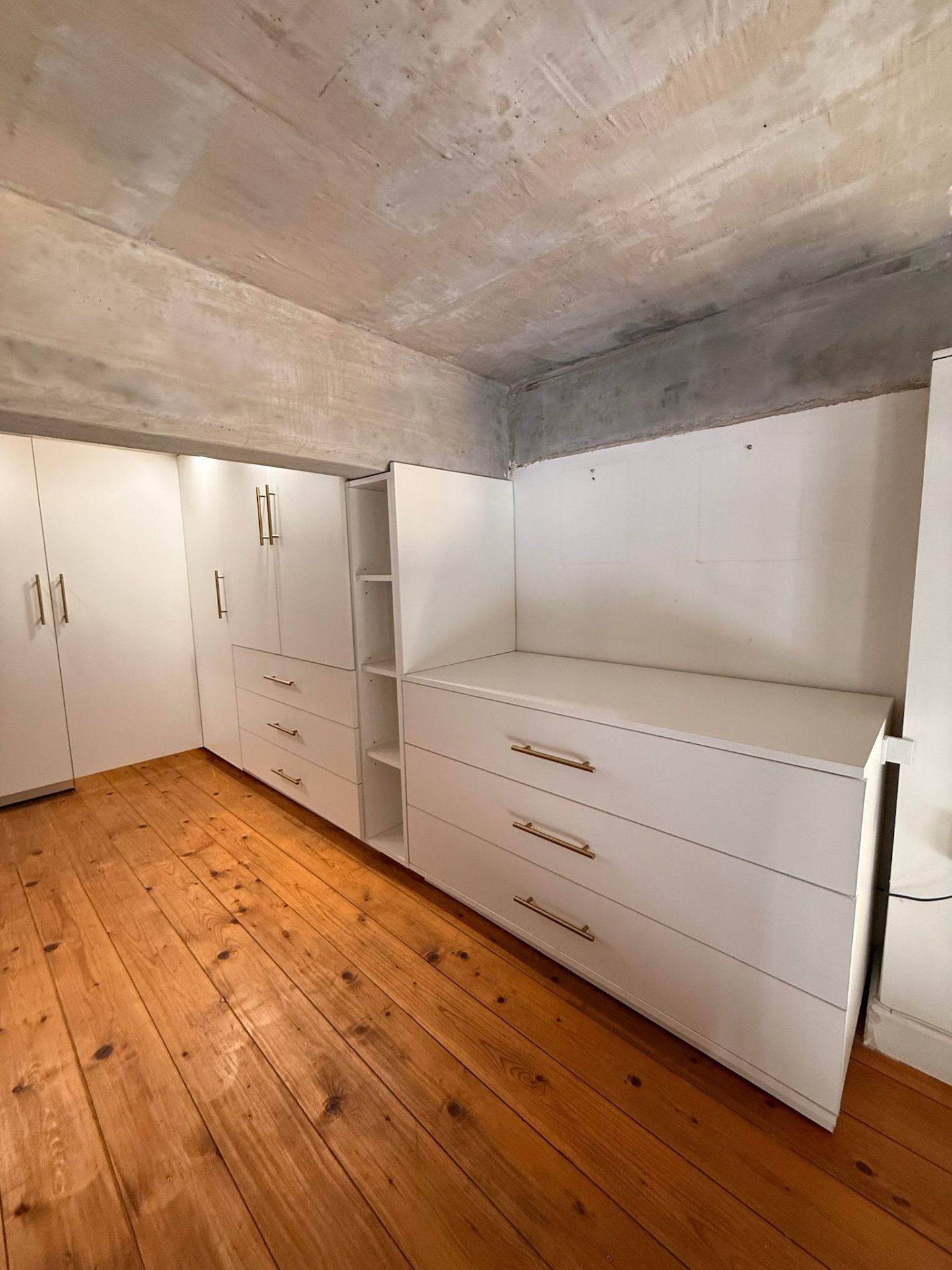 White wardrobe drawers and open shelving in an industrial-style walk-in